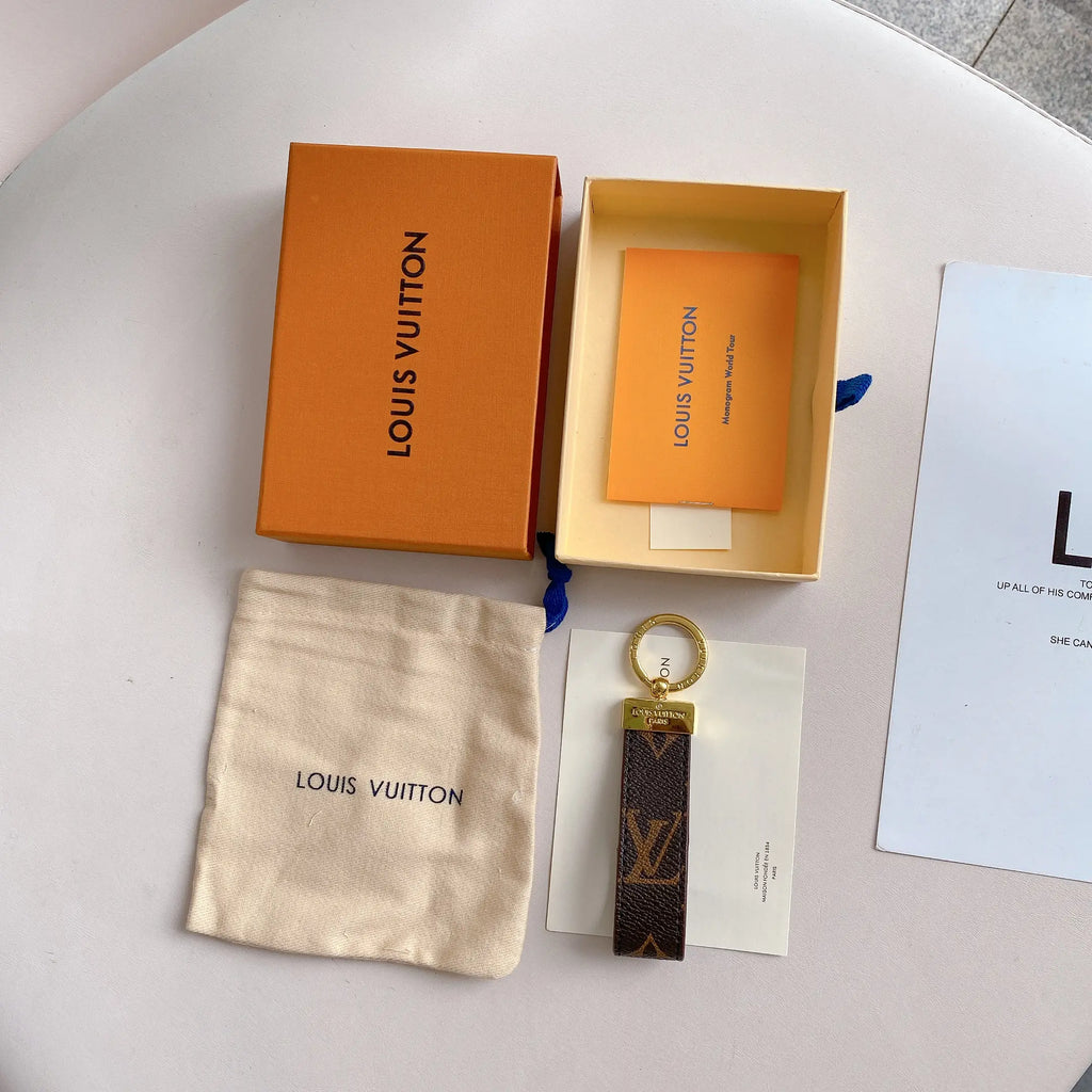 Brown oversized monogram key holder beside pouch and orange box