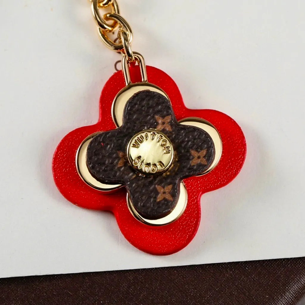 Close-up of red flower pendant with brown monogram center