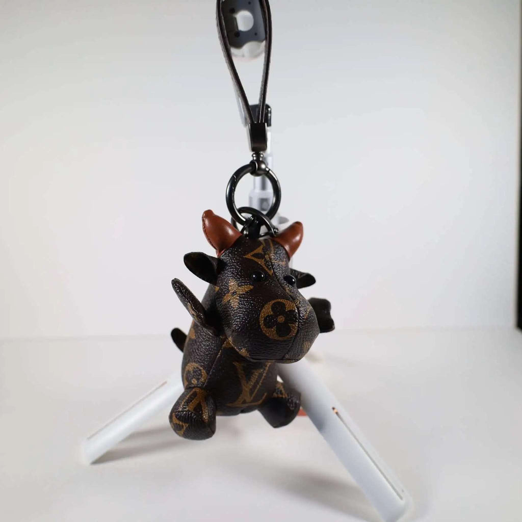 Cow keychain hanging from its wrist strap above a white stand