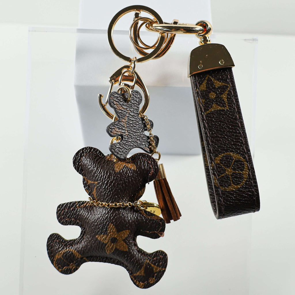 Bear charm hanging beside its brown monogram wrist strap