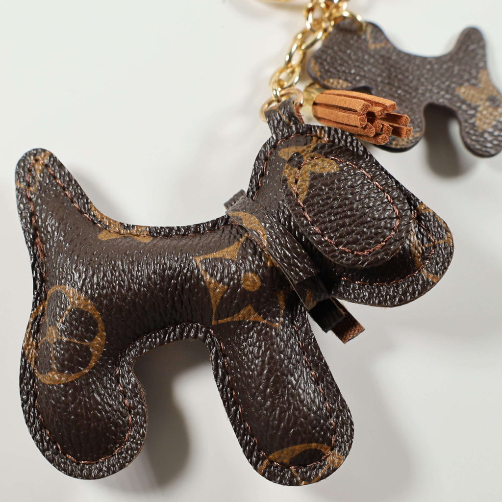 Close-up of brown monogram dog charm and tan tassel