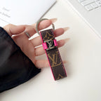 Brown monogram key holder with pink trim held in hand