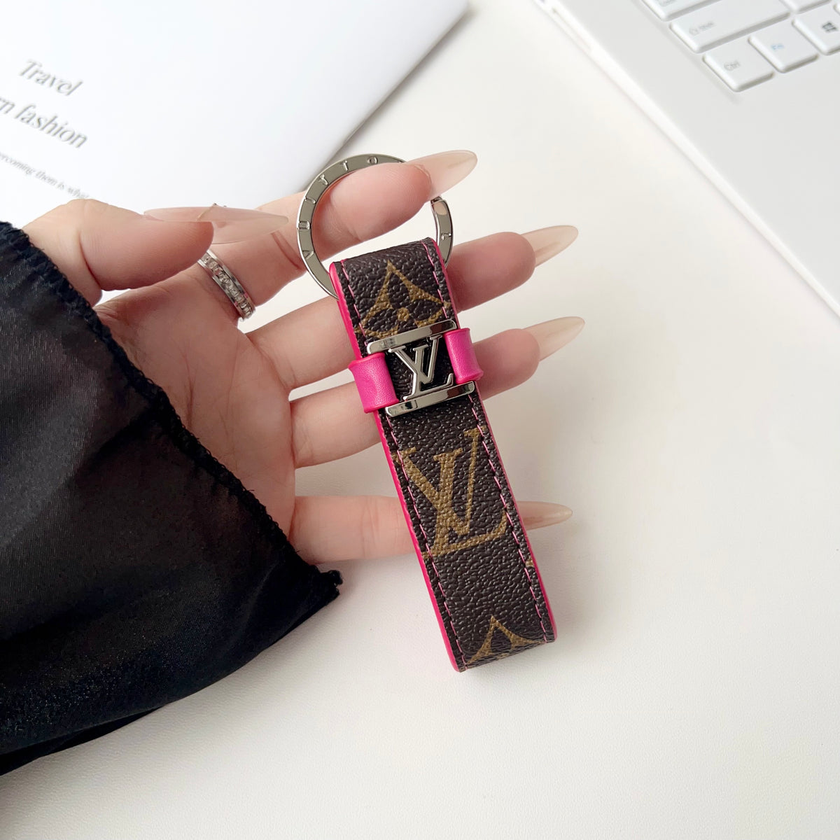 Brown monogram key holder with pink trim held in hand
