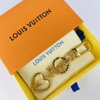 Gold-tone heart keychain arranged on a pouch inside a box