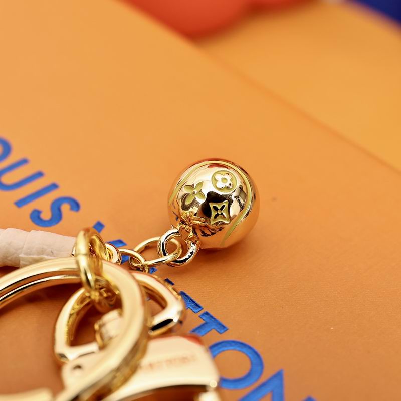 Close-up of gold-tone ball charm on tennis racket keychain