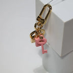 Gold-tone keychain hanging with pink key and lock charms