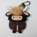 Brown monogram cow keychain with pale fluffy fringe and white horns