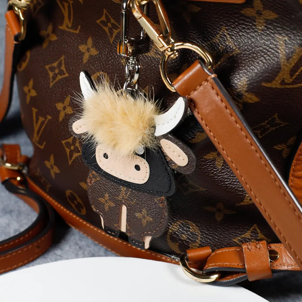 Cow charm with pale fringe attached to a monogram bag