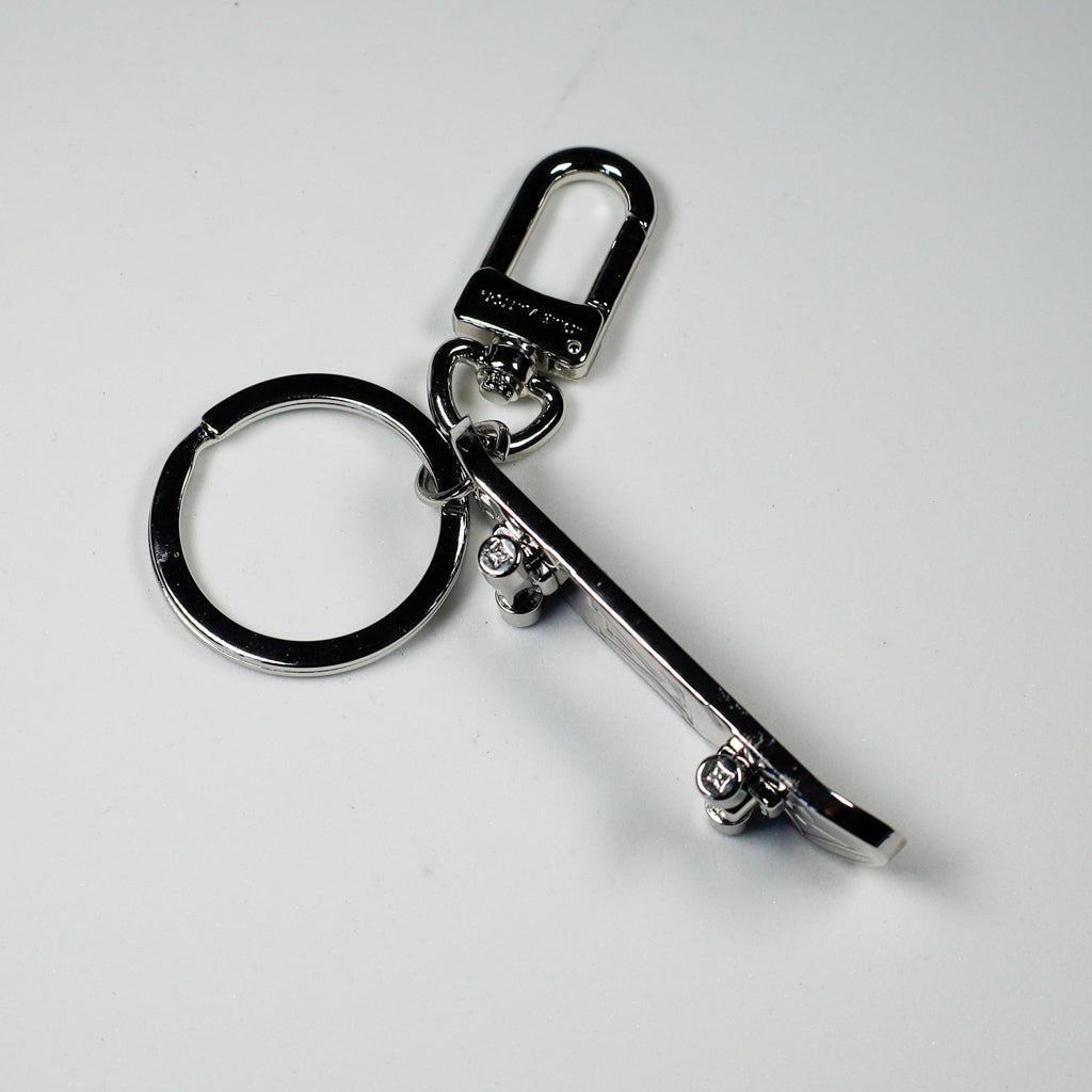 Side view of miniature skateboard keychain showing wheels
