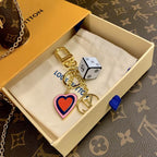 Cube and heart keychain arranged on a pouch inside a box