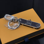 Black monogram skateboard keychain displayed on orange packaging