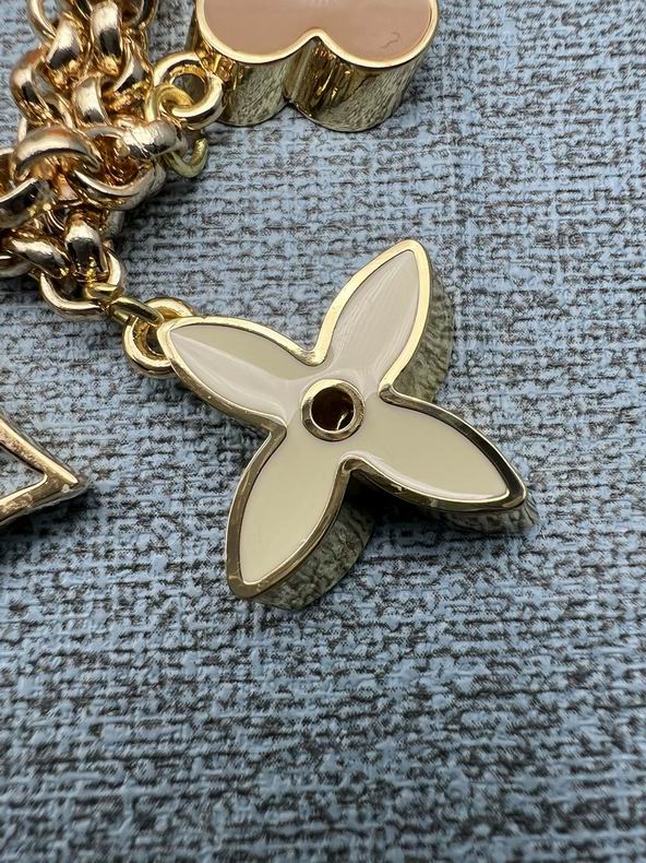 Close-up of pale four-petal flower charm on gold-tone chain