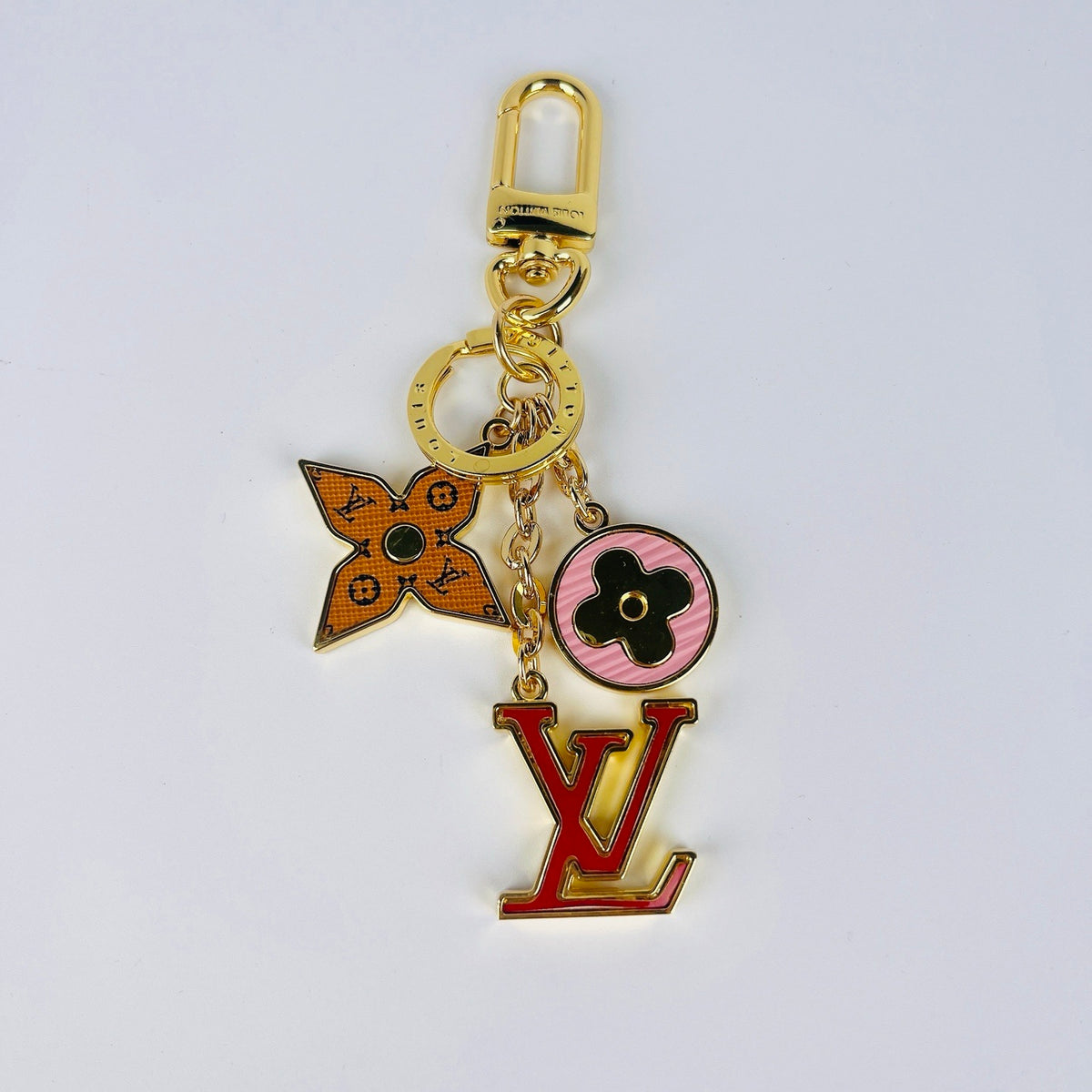 Red LV ornament keychain laid flat with gold-tone ring